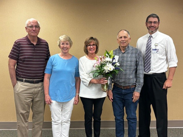 Diane Lawrence, center, is presented with a bouquet in recognition of her 10 years of service as a William Newton Hospital trustee. From left: William Newton Hospital Trustee Steve McSpadden, Trustee Gail Sawyer, Lawrence, Trustee Gary Brewer, and CEO Brian Barta. Not pictured is Trustee Joan Cales.