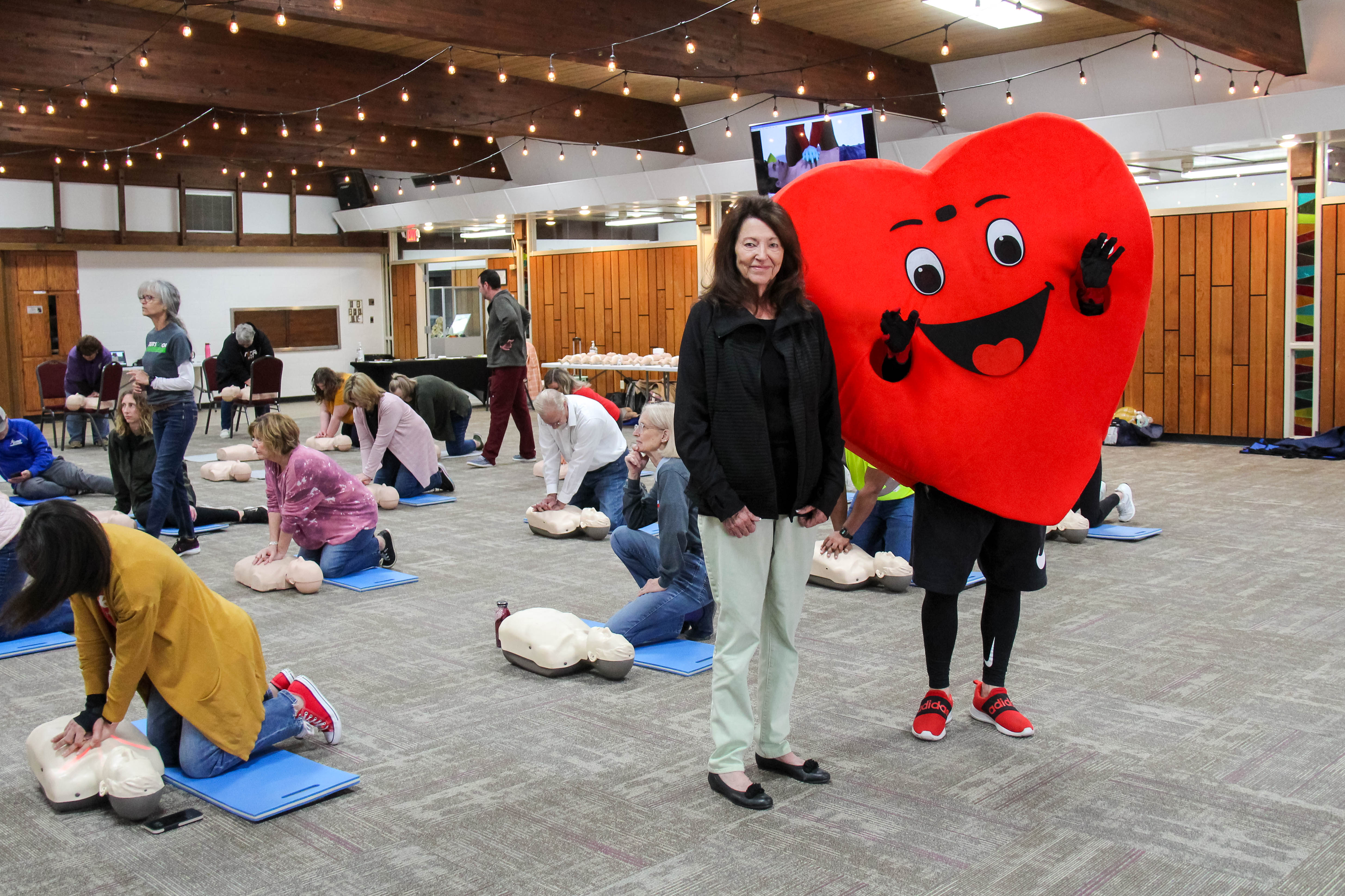 Standing with the Beats Go On mascot Willy Beat, co-chair Paula Radcliff proudly hosts participants in the annual community-wide CPR training at Baden Square in Winfield.